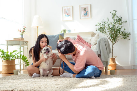 A young couple captures joyful moments with their dog in a bright, cozy living space.の写真素材