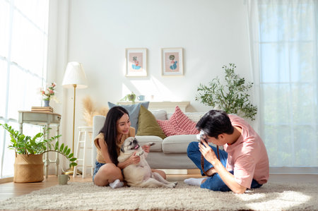 A young couple captures joyful moments with their dog in a bright, cozy living space.の写真素材