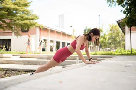 A woman performs a stretching exercise, focusing on her leg muscles under sunlight.の写真素材
