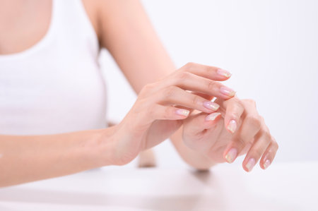 A woman enjoys applying a cream to her hand with a joyful expression in a well-lit setting.の写真素材