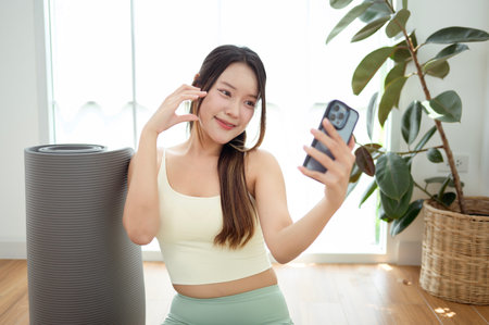 Asian young woman using smart phone after yoga exerciseの写真素材