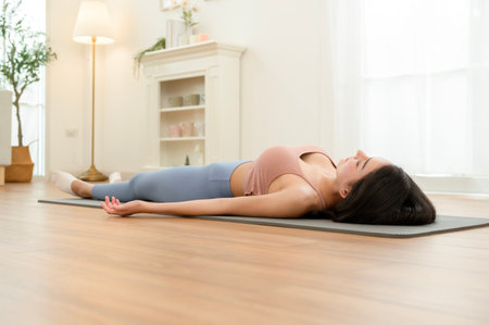 A young woman practices relaxation on a yoga mat in a peaceful indoor environment.