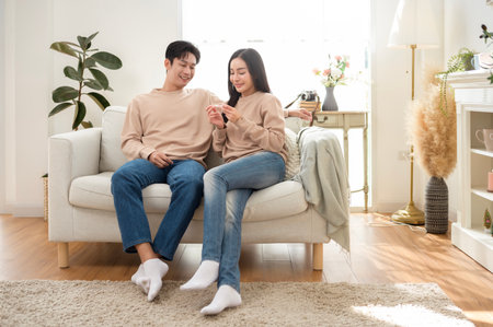 Young couple smiles while holding a pregnancy test, enjoying a happy moment in their home.の写真素材