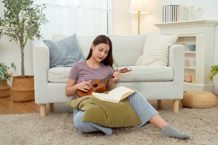 A teenage girl writes lyrics while sitting on a cushion in a bright room filled with plants.の写真素材