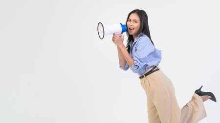 A young woman raises her fist in excitement while holding a megaphone in a studio.