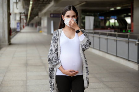 Pregnant woman wearing protective mask outdoors, health and maternity concept.