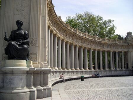 View of the Retiro Garden Lake monument with some tourists resting on the stone bench.の写真素材