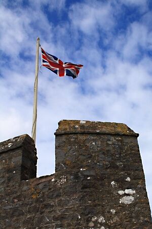 The UK flag waving on a tower of the Pembroke Castle, Wales.の写真素材