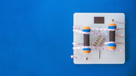 weight loss and physical activity concept from weight scale digital with measure tape for check body shape and workout equipment on yoga matの写真素材