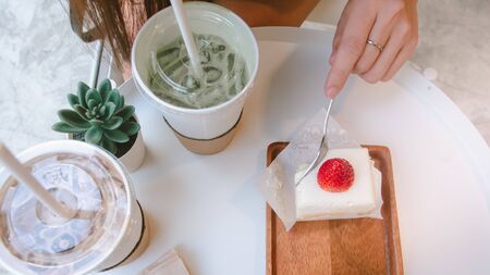 close up of young woman eating cake and drinking coffee at cafe, coffee breakの写真素材