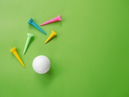 Golf ball with set of rainbow colored tee on green background. top viewの写真素材