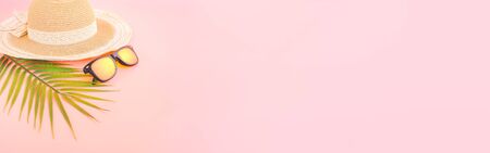 summer accessories concept from sunglasses, straw hat and palm leaf on pastel pink background, for...
