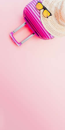 summer travel concept from suitcase with summer accessories on pastel pink background. web banner size.の写真素材