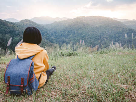 woman hiking with backpack relaxing in nature and enjoy the sunset view on mountain peak at Mae Wong national park Thailand.の素材 [FY310152986875]