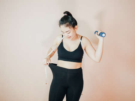 Lose belly fat concept from close up woman in sportswear with hand holding her own belly fat and...