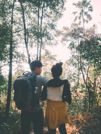 Adventure travel concept from Happy young couple are enjoying hiking trip in summer season with sun shining through trees.の写真素材