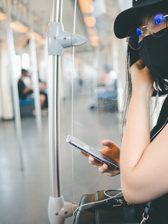 close-up woman wear protective mask and using smartphone in public transport.の写真素材