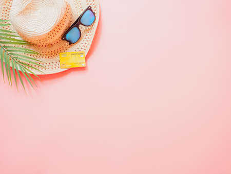 summer accessories concept from credit card and summer collection on pastel red background.