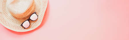 summer accessories concept from sunglasses and straw hat on pastel red background. web banner size.の写真素材
