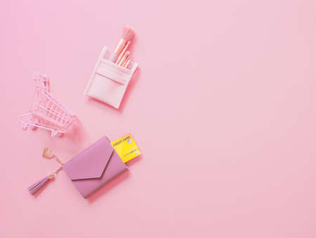 shopping cosmetic and payment concept from pink wallet with credit cards, blush brush set and trolley on pink background.の写真素材