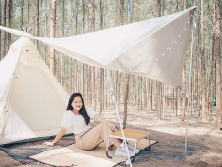 Happy Asian teenage girl in front of camp tent. Outdoor activity. Adventure travel and holiday...