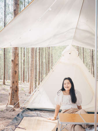 Happy Asian teenage girl in front of camp tent. Outdoor activity. Adventure travel and holiday vacation concept.の写真素材