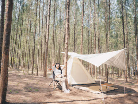 Happy Asian teenage girl in front of camp tent. Outdoor activity. Adventure travel and holiday vacation concept.の写真素材