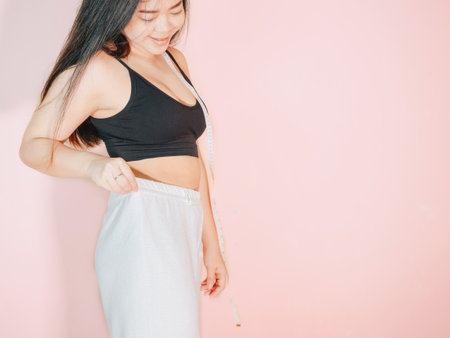 Lose belly fat concept from close up woman in sportswear with hand holding her own belly fat and cellulite.の写真素材