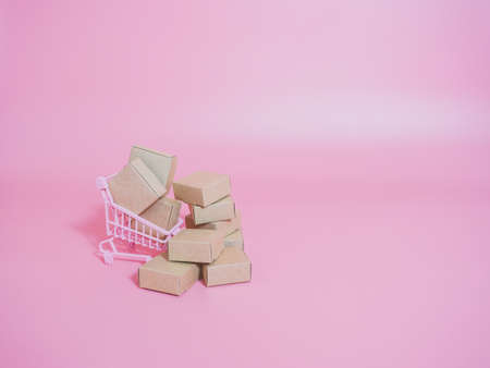 Shopping cart and boxes on pink background. Logistics and wholesale concept.の写真素材