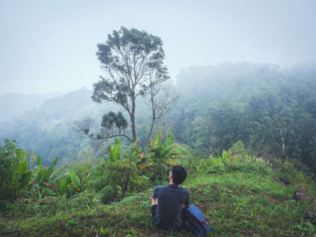 Alone man hiking enjoyment the morning mist in lush tropical rainforest.の写真素材