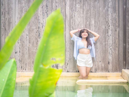 Chubby happy young asian woman dressed in swimsuit near swimming pool.