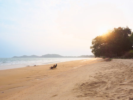 Traveller couple sitting and see sunset together on the beach.の写真素材