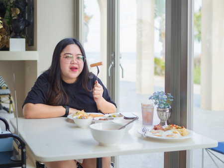 Curvy Asian woman enjoying breakfast. Real body lifestyle with confidence and happiness.