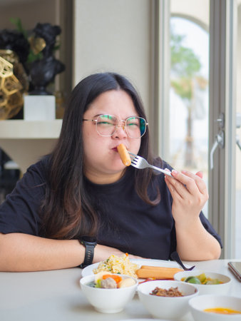 Curvy Asian woman enjoying breakfast. Real body lifestyle with confidence and happiness.の写真素材