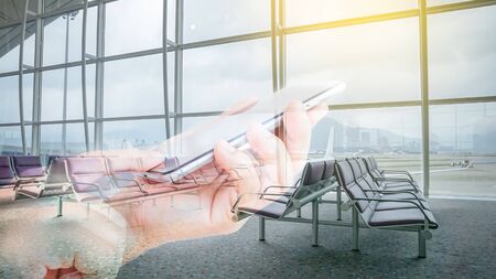 Double exposure of hand hold and touch screen smart phone with airport blurry background.の写真素材