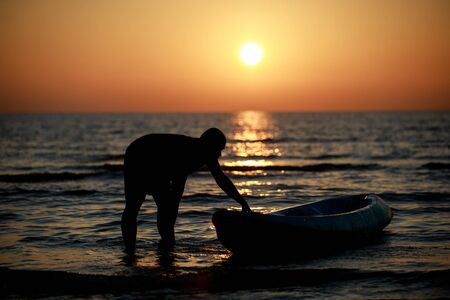 Boat on the beach behind the beautiful sunsetの写真素材