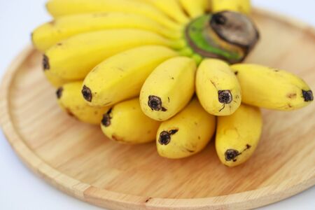 Bananas on a wooden plate, isolated on white backgroundの写真素材