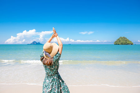 Portrait of young pretty woman looking to the ocean on the tropical beach, wearing stylish hat and clothes.の写真素材