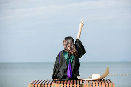 Women  a graduation  clothing sit  at the beach, Relaxing  summer holiday and travelの写真素材