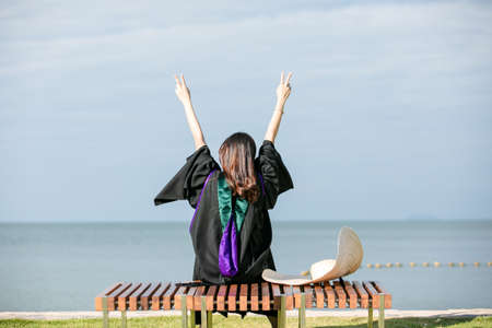 Women  a graduation  clothing sit  at the beach, Relaxing  summer holiday and travelの写真素材