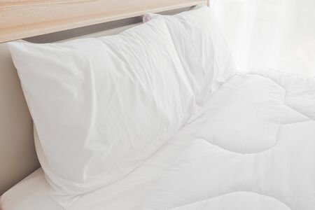 Bedroom interior with bed and flowers on nightstand.White bedroom interior with double bed on a...