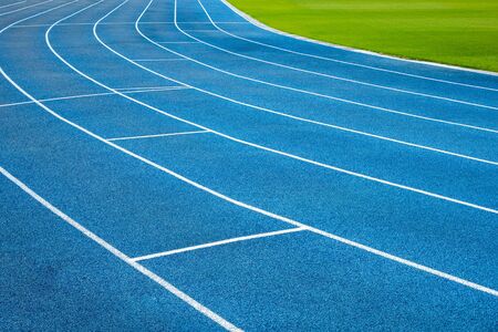 Blue running treadmill track with lane numbers in stadium outdoors.Starting grid of race track at the stadiumの写真素材