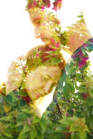 Double exposure of a couple with melancholic sad expression dissolving behind tropical plantsの写真素材