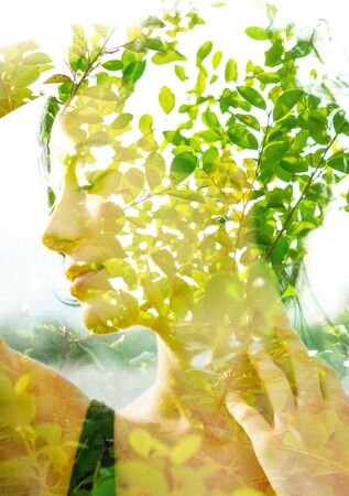 Double exposure portrait of a young, natural beauty with short hair and hand on neck combined with green tropical leaves on an isolated white backgroundの写真素材