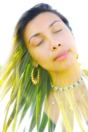 Double exposure portrait of a young, relaxed natural beauty with head tilted sideways and long brown...