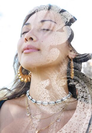 Double exposure profile portrait of young female traveller combined with close up of a rock sculpture from a Balinese temple in southeast asiaの写真素材