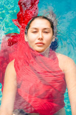 Attractive lady swimming in a red dressの写真素材
