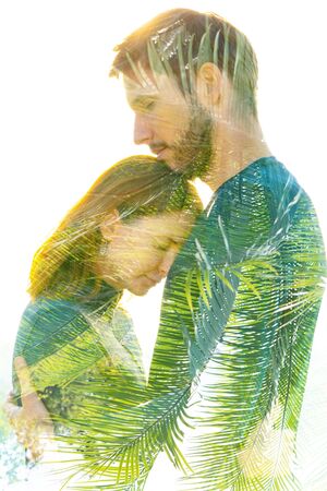Double exposure portrait of man and woman happily embracing and dissolving into healthy tropical plantsの写真素材
