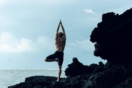 Athlete man practicing yoga outdoors photographの写真素材