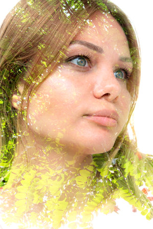 A double exposure portrait of a young blue eyed thoughtful woman with light green fern on white...